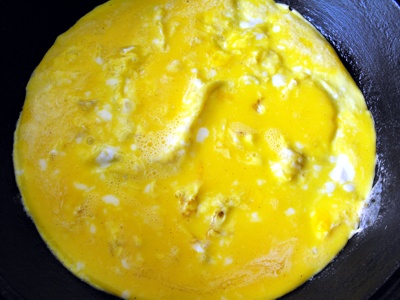 Step 3 - Pour egg into pan win hot oil, pierce to let air out and let set at low heat