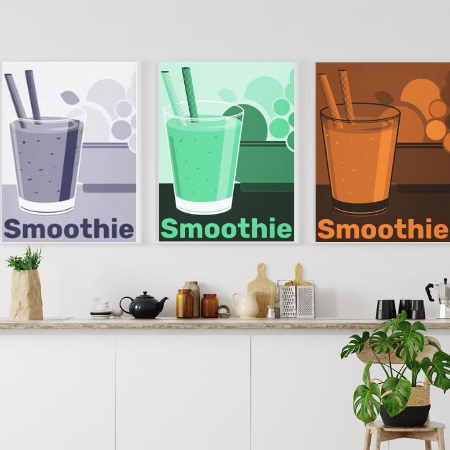 white dining area decorated with digital art poster prints showing a smoothie tumbler with straw and a bowl of fruits, one print shows monochrome pastel blue, the second in green, the third in orange